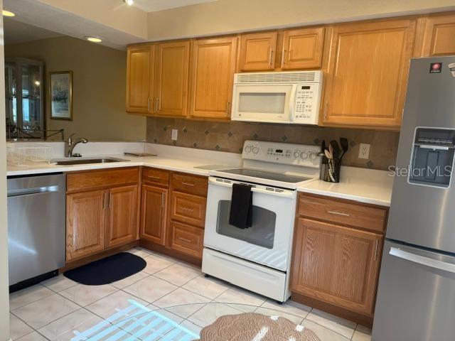 A kitchen features light wood cabinets, stainless steel appliances, and a white tiled floor — 105 LAKEVIEW WAY UNIT 105, OLDSMAR, FL