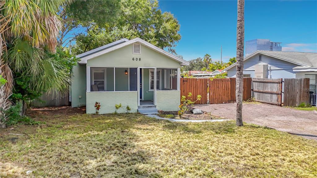 A light green house with a screened-in front porch stands behind a grassy yard — 608 N LINCOLN AVENUE, TAMPA, FL