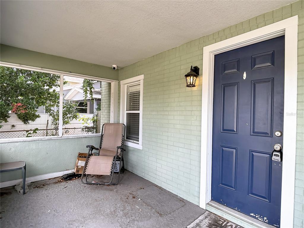 A covered porch features a blue front door, light green brick walls, and a lounge chair — 608 N LINCOLN AVENUE, TAMPA, FL