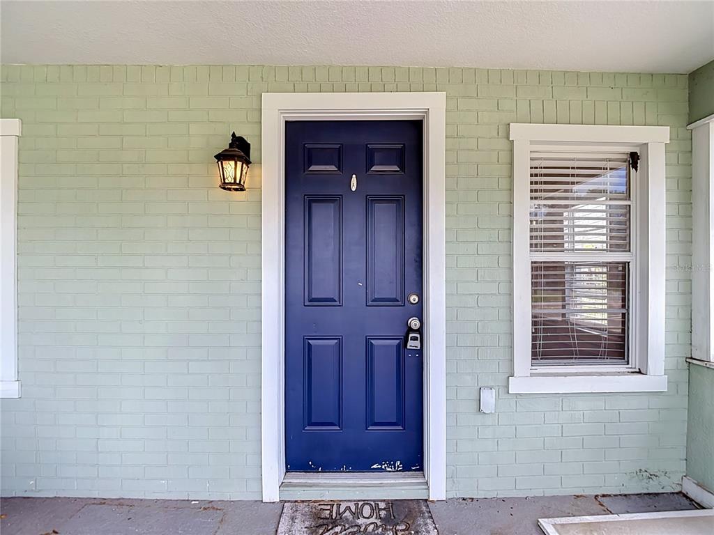 A blue front door is centered on a light green painted brick exterior wall — 608 N LINCOLN AVENUE, TAMPA, FL