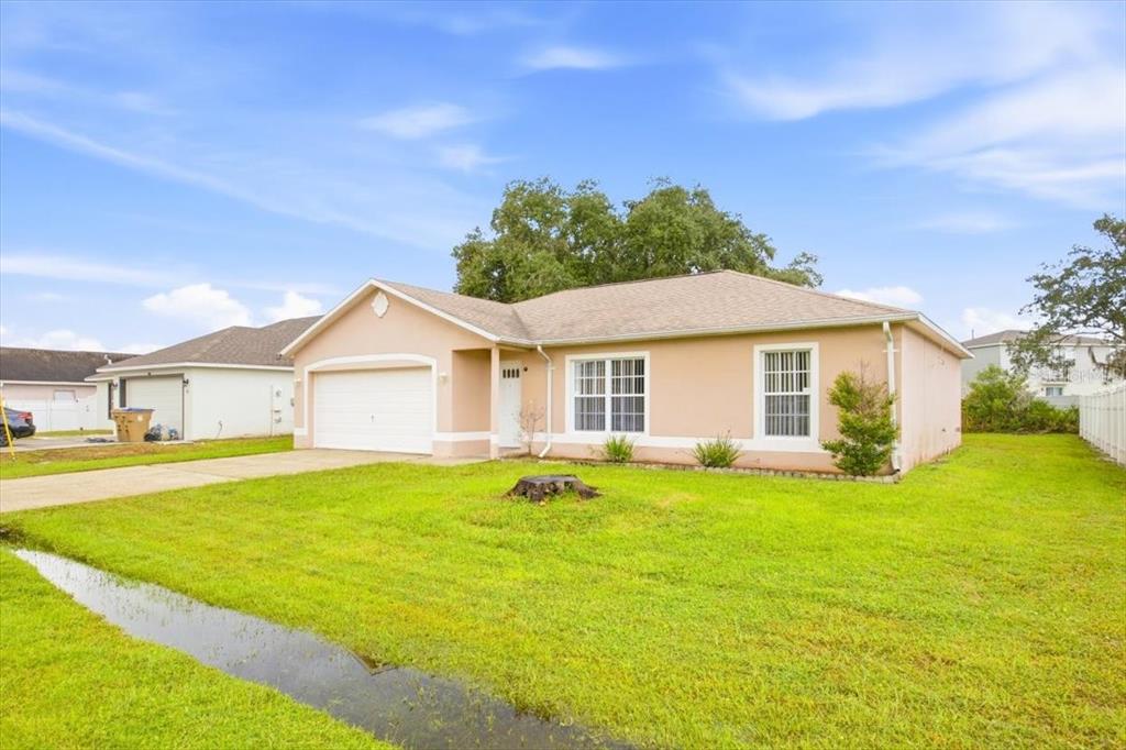 An empty room with tan tile flooring, a vaulted ceiling, and a sliding glass door — 718 PINCON LANE, KISSIMMEE, FL