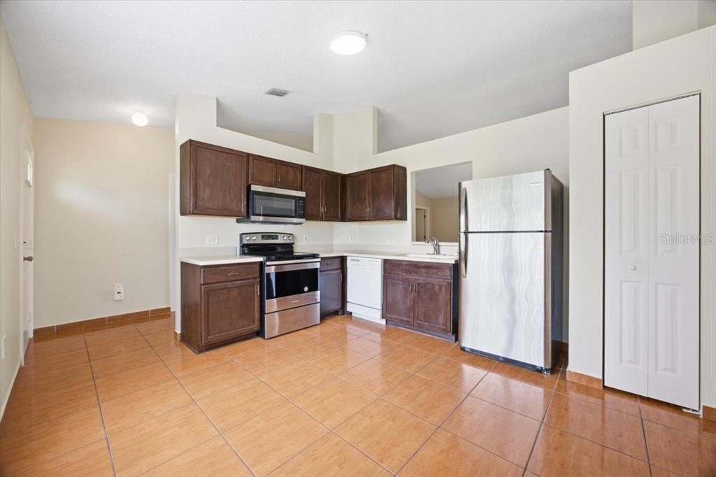 An empty room with tiled floors, a chandelier, and a pass-through window to the kitchen — 718 PINCON LANE, KISSIMMEE, FL