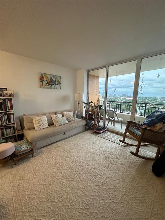 A living room features a beige sofa, a rocking chair, and floor-to-ceiling windows with balcony access — 3232 CORAL WAY UNIT 1607, MIAMI, FL