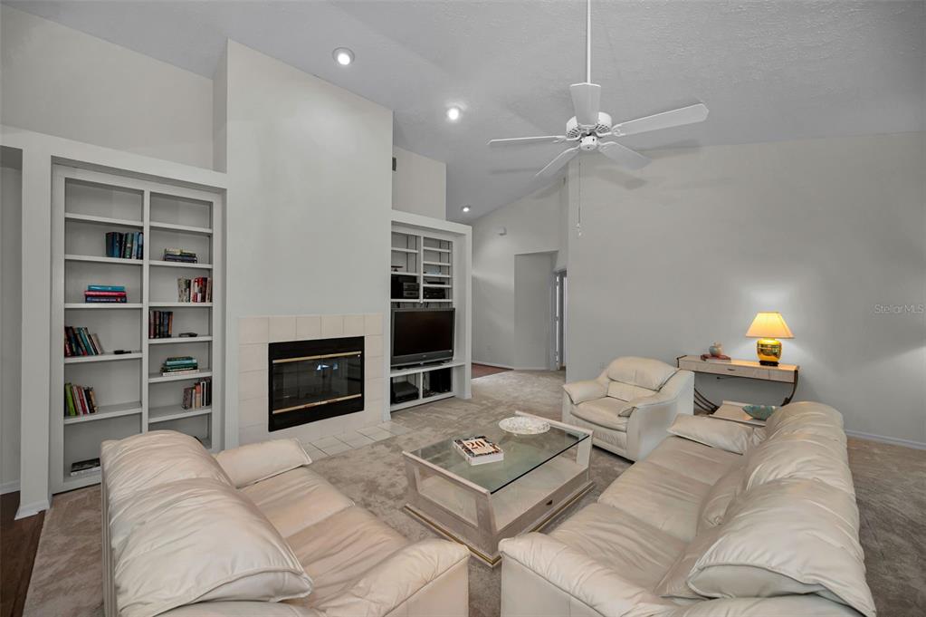 A living room features a fireplace, built-in shelving, a ceiling fan, and white leather furniture — 900 LUCAS LANE, OLDSMAR, FL