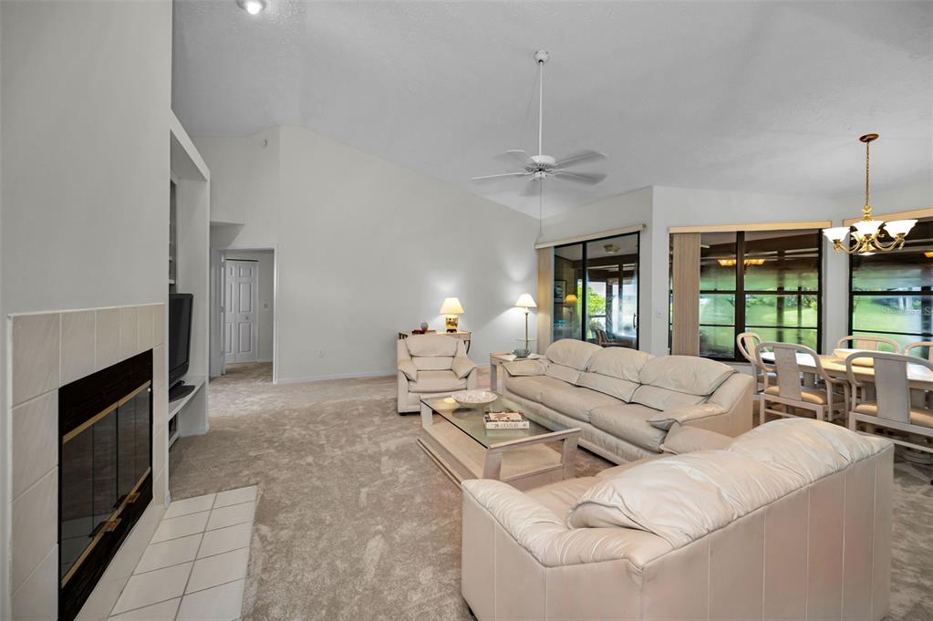A living room with a fireplace, white leather furniture, and a dining area — 900 LUCAS LANE, OLDSMAR, FL