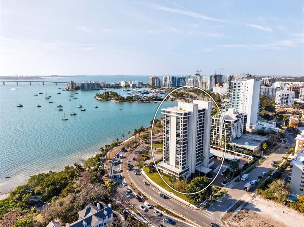 A modern lobby features purple armchairs, a reception desk, and floor-to-ceiling windows overlooking a patio — 770 S PALM AVENUE UNIT PH2, SARASOTA, FL