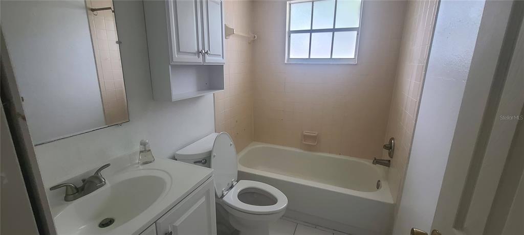 A bathroom features a white vanity, a toilet, and a bathtub with beige wall tiles — 580 FAIRWAYS LANE UNIT G203, OCALA, FL