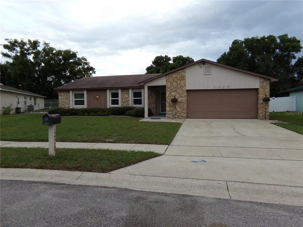 A single-story house features a stone facade, a brown garage door, and a grassy lawn — 1320 GLADIOLAS DR, WINTER PARK, FL