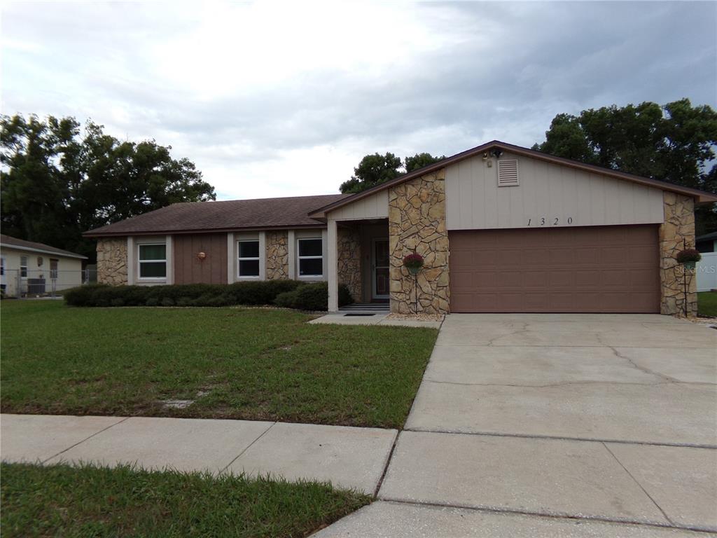 A single-story house with a stone facade, brown siding, and an attached two-car garage — 1320 GLADIOLAS DR, WINTER PARK, FL