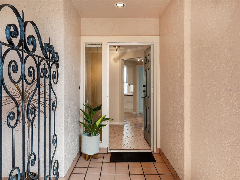 An entryway features a decorative metal gate, tiled floor, and a door opening into a hallway — 5420 EAGLES POINT CIRCLE UNIT 106, SARASOTA, FL