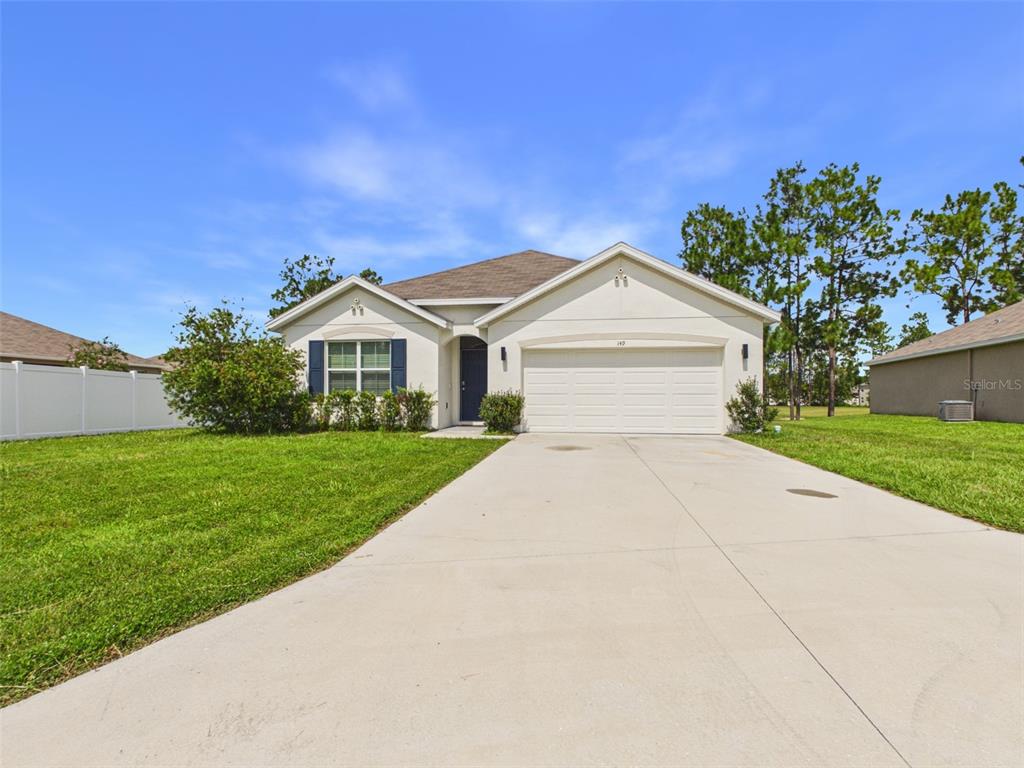 A single-story house with a white garage, blue shutters, and a concrete driveway — 149 HICKORY COURSE CIRCLE, OCALA, FL