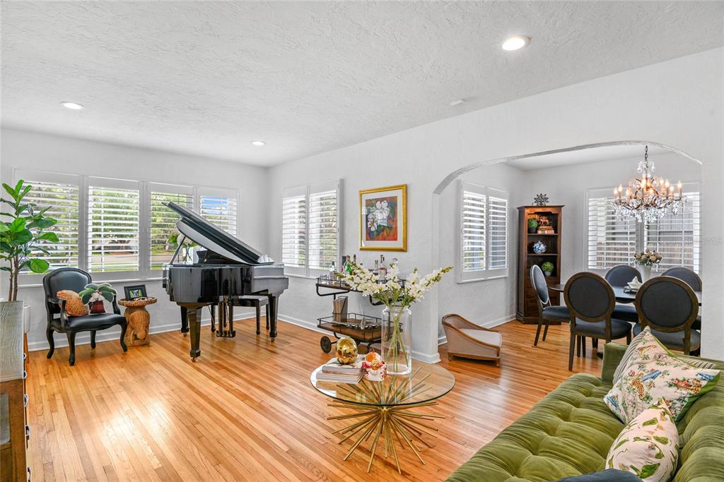 A living room with hardwood floors features a grand piano, a glass coffee table, and dining area — 505 WESTMINSTER STREET, ORLANDO, FL