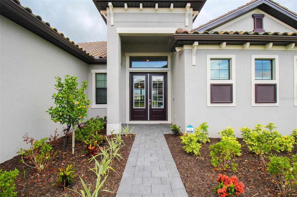 The exterior of a house features a paved walkway leading to dark double front doors — 16106 TRADEWIND TERRACE, BRADENTON, FL