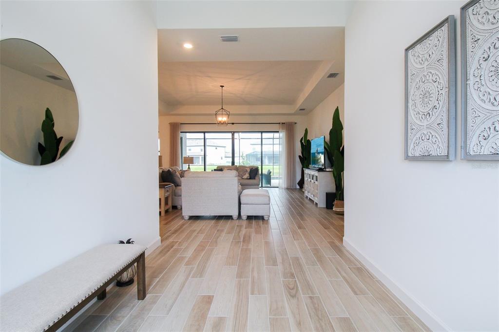 A bright entryway leads into a living room with tile floors and a tray ceiling — 16106 TRADEWIND TERRACE, BRADENTON, FL