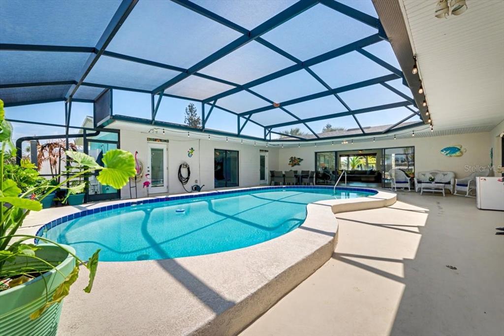 A screened-in patio features a kidney-shaped swimming pool and outdoor seating area — 124 ANCHOR DRIVE, PONCE INLET, FL