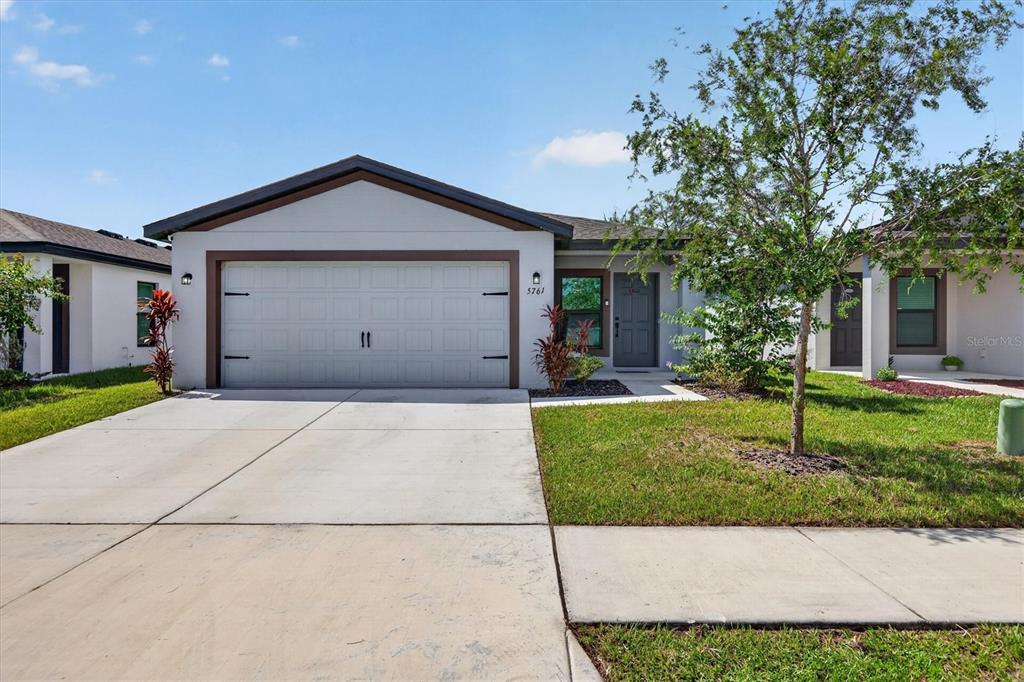 A single-story house with a two-car garage, a gray front door, and a concrete driveway — 5761 HELMSMAN COURT, TAMPA, FL