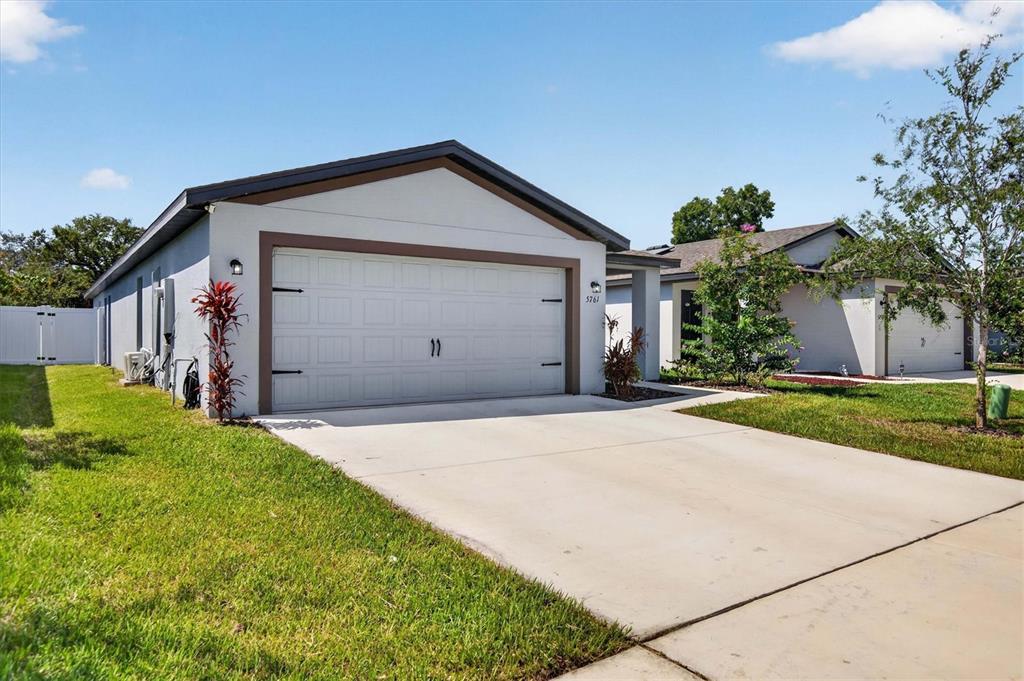 A single-story house with a two-car garage and a concrete driveway under a blue sky — 5761 HELMSMAN COURT, TAMPA, FL