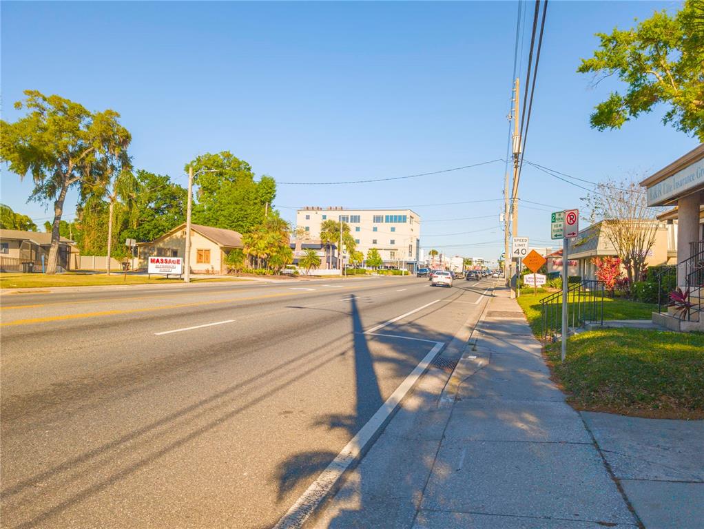 A street view showing a road, sidewalk, utility poles, and nearby commercial buildings under a clear sky — 802 E COLONIAL DRIVE, ORLANDO, FL