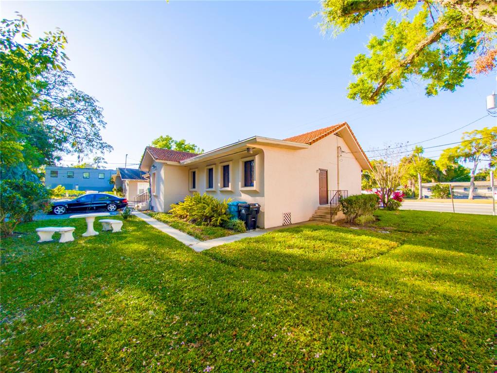 A side view of a single-story house with a lawn, driveway, and outdoor seating — 802 E COLONIAL DRIVE, ORLANDO, FL
