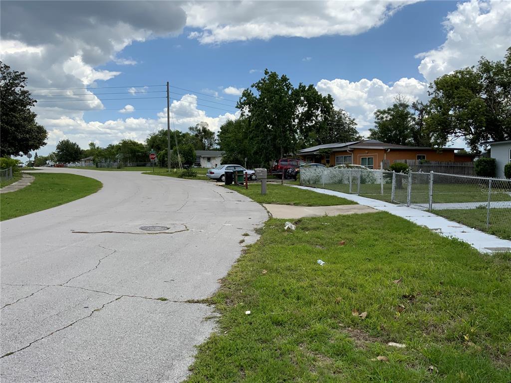 A street view showing a residential road, a chain-link fence, and a single-story house — HASTINGS DRIVE, DELTONA, FL
