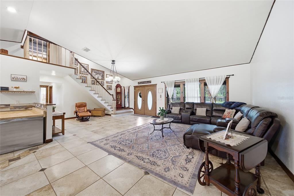 A spacious living room features tile flooring, a staircase, and a large brown sectional sofa — 22289 CHERATON ROAD, BROOKSVILLE, FL