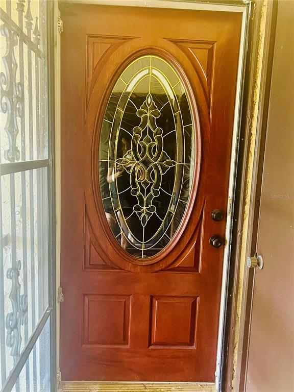 A wooden front door with an oval glass insert and a decorative metal security gate — 625 MIDWAY DRIVE UNIT B, OCALA, FL