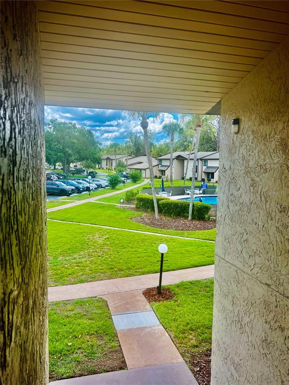 A view from a covered patio overlooking a grassy courtyard, swimming pool, and apartment buildings — 625 MIDWAY DRIVE UNIT B, OCALA, FL