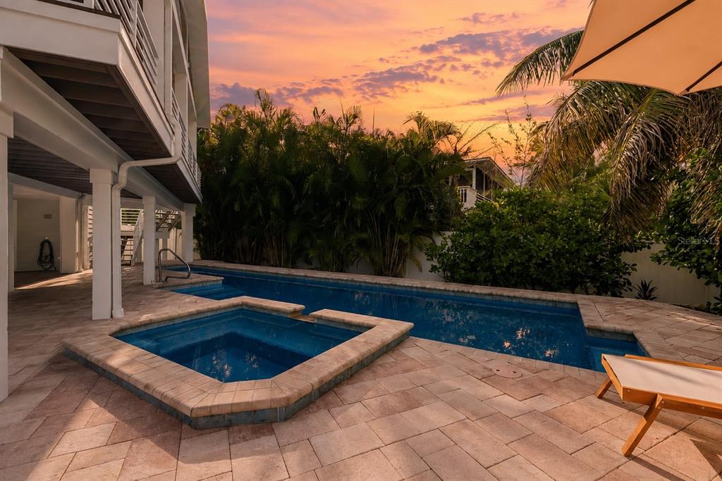 A rectangular swimming pool and attached spa sit on a paved patio beside a house — 315 HAMMOCK CIRCLE, ANNA MARIA, FL