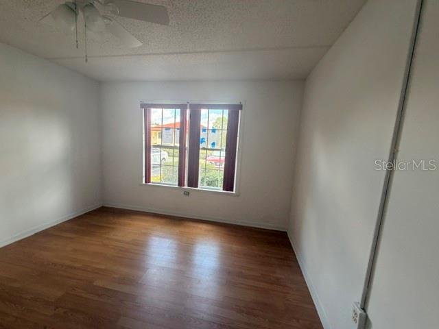 An empty bedroom features wood-look flooring, white walls, a ceiling fan, and a window — 2400 FOREST DRIVE UNIT 103, INVERNESS, FL
