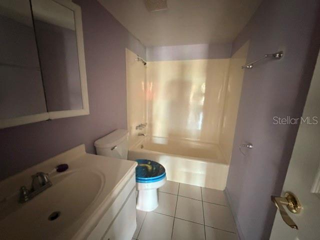 A bathroom with a white vanity, a toilet with a blue lid, and a tub-shower combo — 2400 FOREST DRIVE UNIT 103, INVERNESS, FL