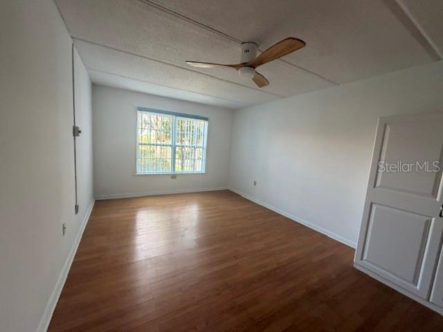 An empty room features wood-look flooring, white walls, a ceiling fan, and a window — 2400 FOREST DRIVE UNIT 103, INVERNESS, FL