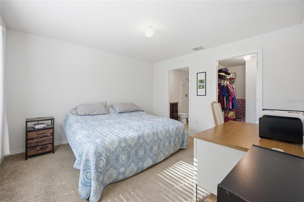 A bedroom features a bed, a nightstand, a desk, and doorways leading to a bathroom and closet — 273 HICKORY COURSE RADIAL, OCALA, FL