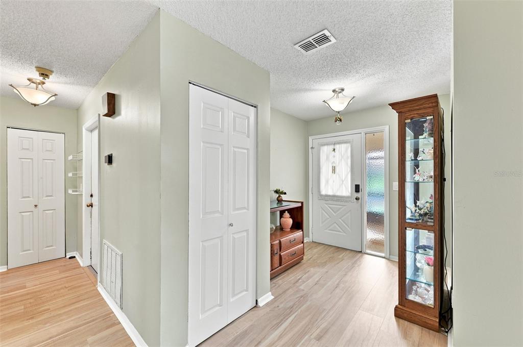 An entryway features light wood-look flooring, white paneled doors, and a tall glass display cabinet — 1618 LAYTON COURT, SUN CITY CENTER, FL