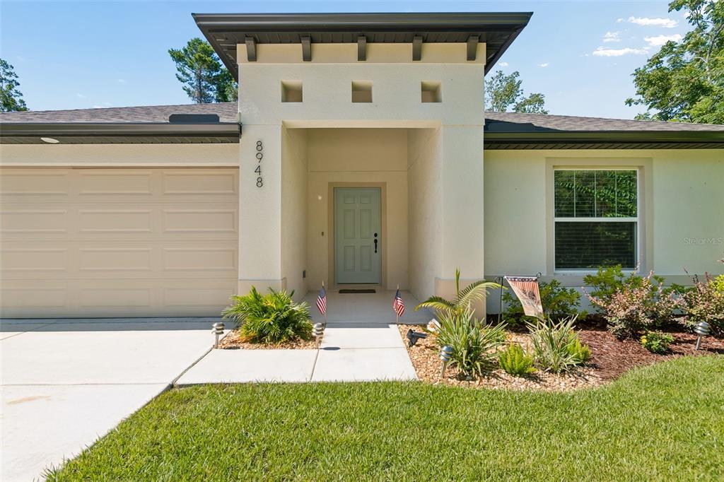 A single-story house with a beige exterior, a two-car garage, and a front lawn — 8948 CARRIE WAY, WEEKI WACHEE, FL