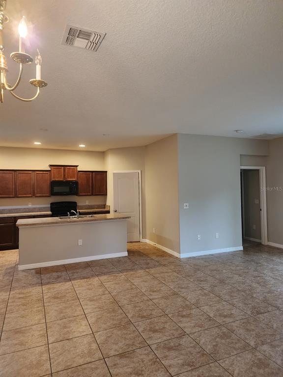 An open-concept kitchen features dark wood cabinets, a breakfast bar, and light-colored tile flooring — 2765 CARRICKTON CIRCLE, ORLANDO, FL
