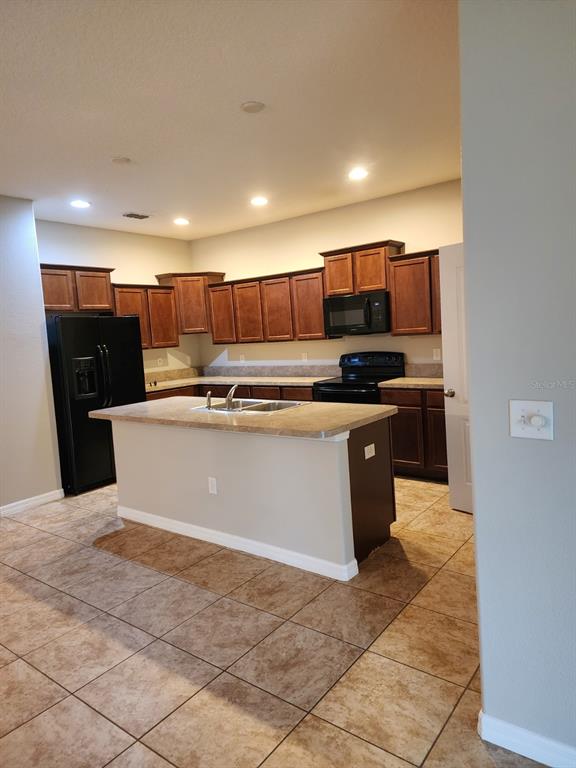 A kitchen with dark wood cabinets, a central island with a sink, and black appliances — 2765 CARRICKTON CIRCLE, ORLANDO, FL