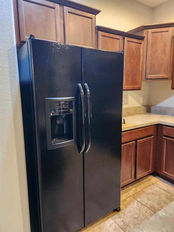 A black side-by-side refrigerator stands in a kitchen with brown wood cabinets and countertops — 2765 CARRICKTON CIRCLE, ORLANDO, FL