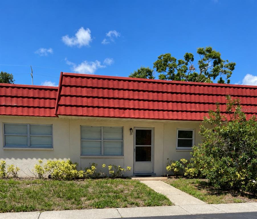 An empty living room features beige carpeting, light-colored walls, a front door, and vertical blinds — 5860 38TH AVENUE N UNIT 29, ST PETERSBURG, FL