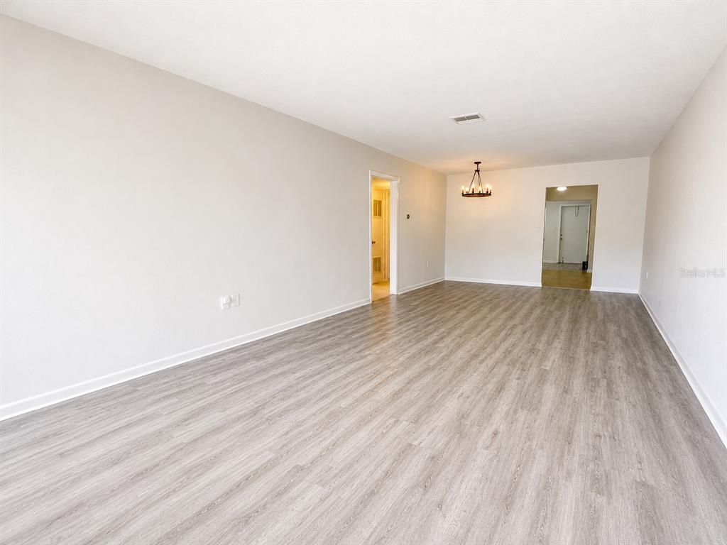 This room features beige carpeting, light-colored walls, and a rustic chandelier above a wall mirror — 5860 38TH AVENUE N UNIT 29, ST PETERSBURG, FL