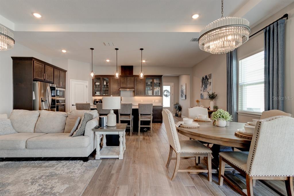 An open-concept living and dining area features dark wood cabinetry, pendant lighting, and tile flooring — 828 MIDDLETON STREET, DEBARY, FL