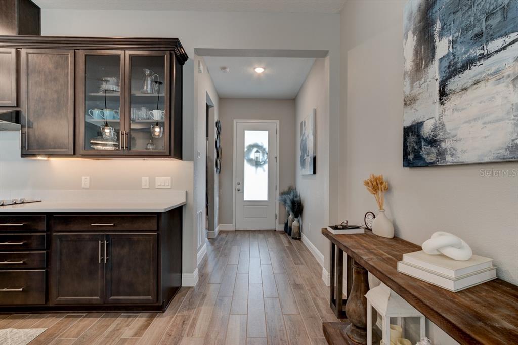 A kitchen with dark cabinets and a hallway leading to a white front door — 828 MIDDLETON STREET, DEBARY, FL