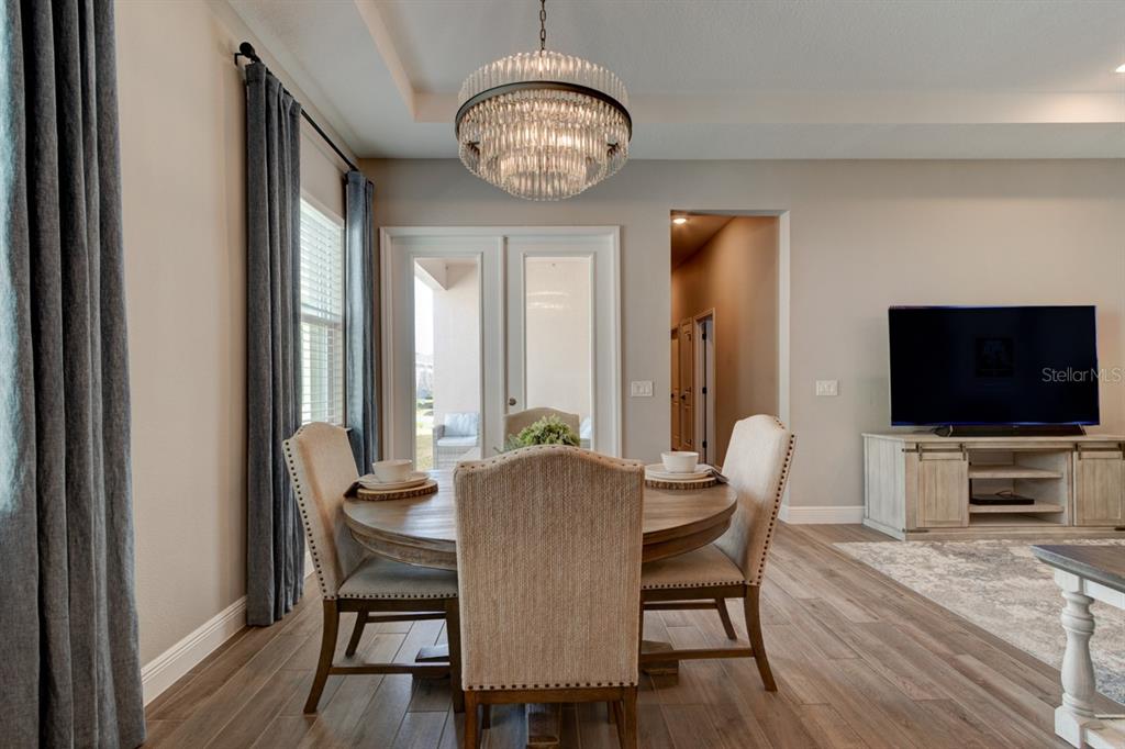 A dining area features a round wooden table, upholstered chairs, and a tiered crystal chandelier — 828 MIDDLETON STREET, DEBARY, FL