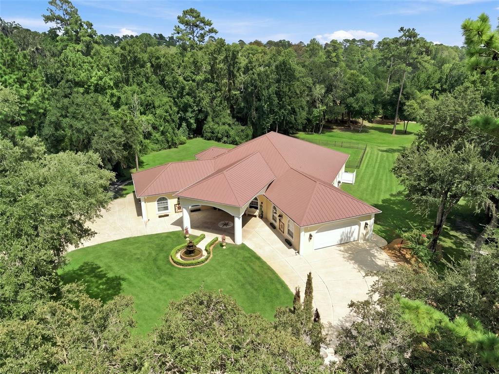 An aerial view of a single-story house with a metal roof and a circular driveway — 22259 SKYVIEW CIRCLE, BROOKSVILLE, FL