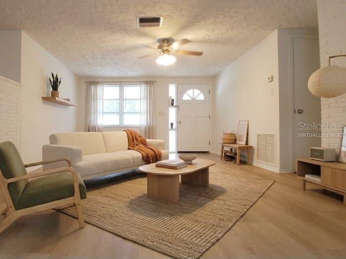 A living room features light wood-look flooring, white walls, a ceiling fan, and exterior doors — 2109 SHANNON DRIVE, HOLIDAY, FL
