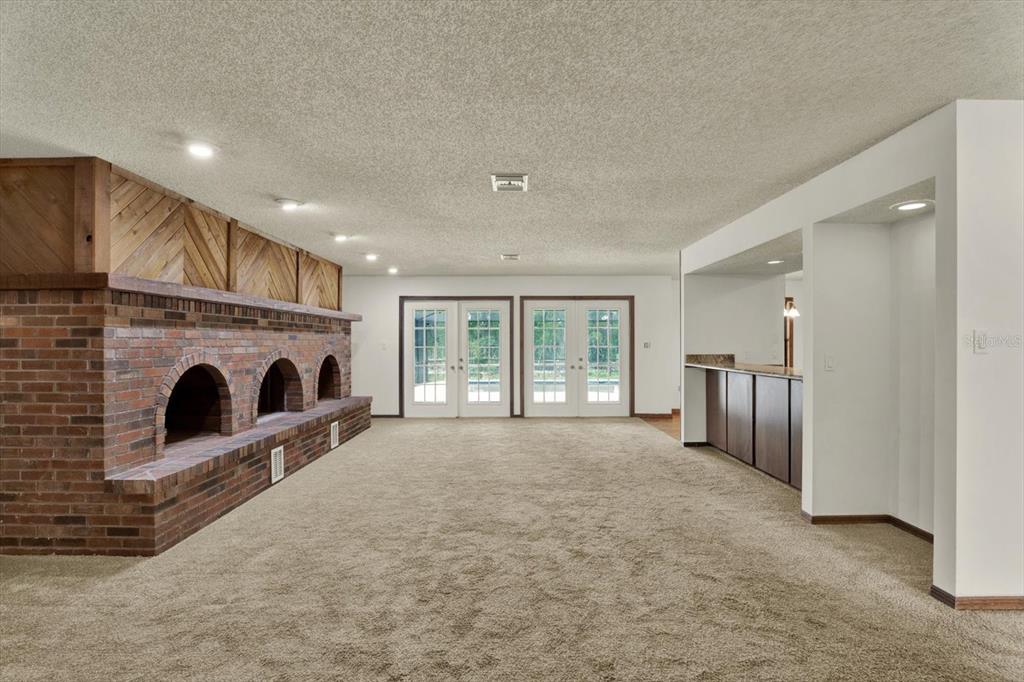 A large carpeted room features a brick fireplace with three arches and a built-in bar — 11251 SALINA STREET, BROOKSVILLE, FL