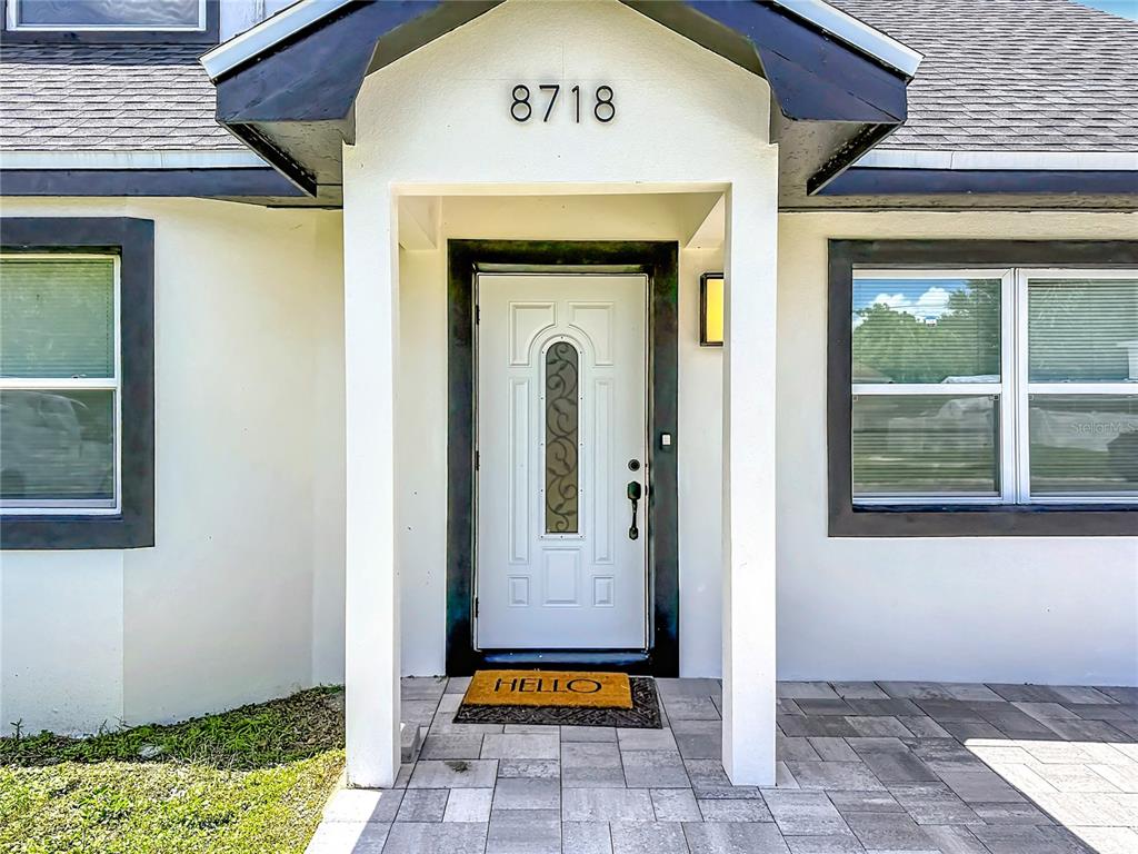 The exterior entrance features a white front door with a decorative glass insert and house numbers — 8718 94TH ST, SEMINOLE, FL