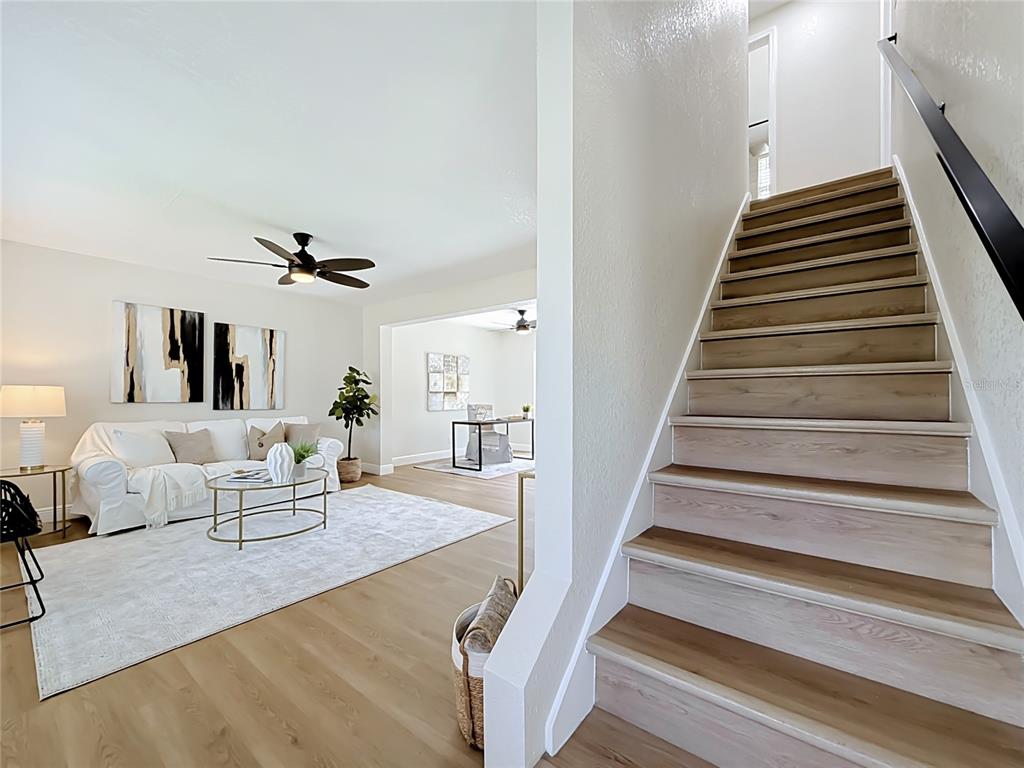 A living room with a white sofa and stairs leading to an upper floor — 8718 94TH ST, SEMINOLE, FL