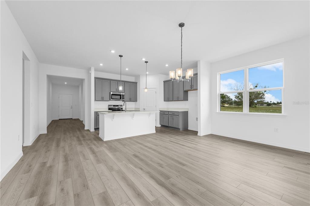 A modern kitchen with grey cabinets and a white island opens to a living area — 1112 BANFF DRIVE NE, PALM BAY, FL