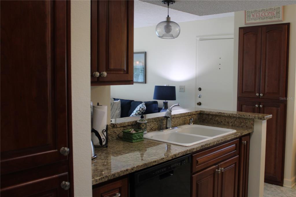 A kitchen features wood cabinets, granite countertops, black appliances, and a white tile backsplash — 327 108TH STREET W UNIT 327, BRADENTON, FL