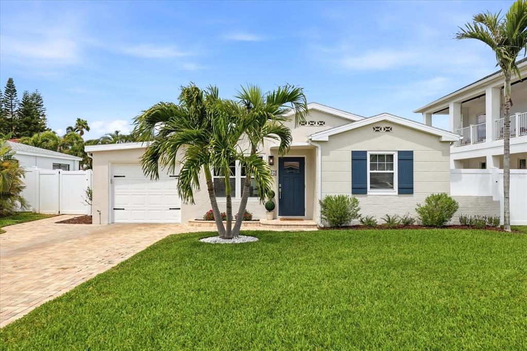 A single-story house with a white garage, blue front door, and a palm tree — 105 3RD STREET, BELLEAIR BEACH, FL